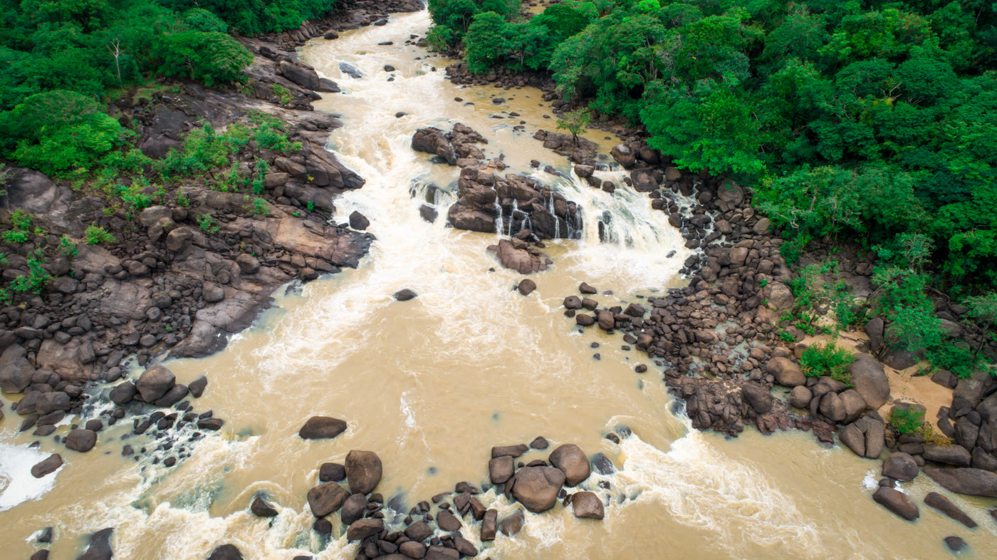 Vista aérea do rio e das pedras da cachoeira da Manoa, cercados pela floresta